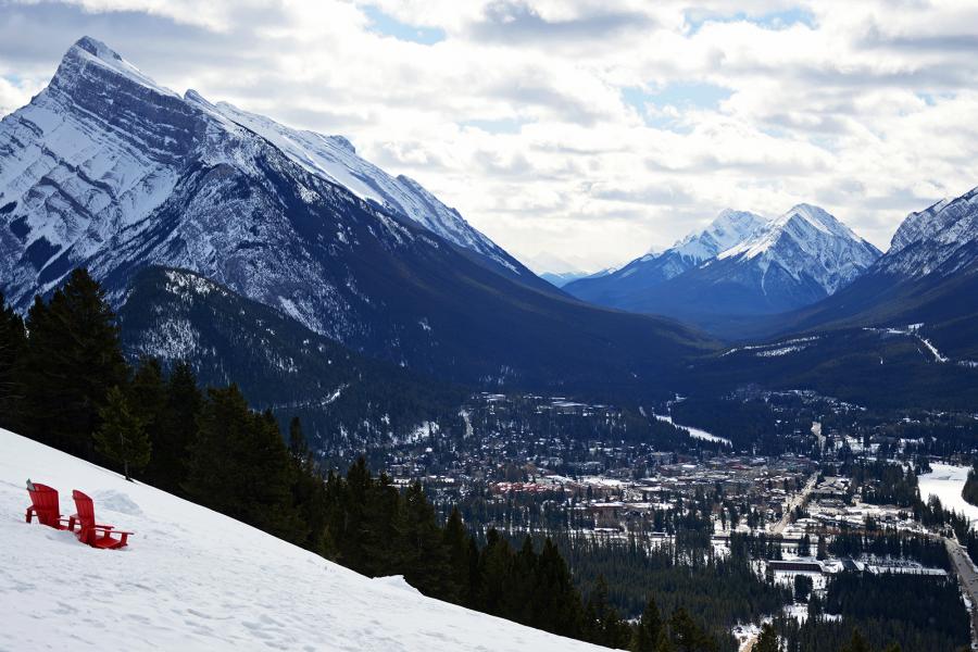 Parks Canada red Muskoka chairs on a snowy slope overlooking the Banff townsite 